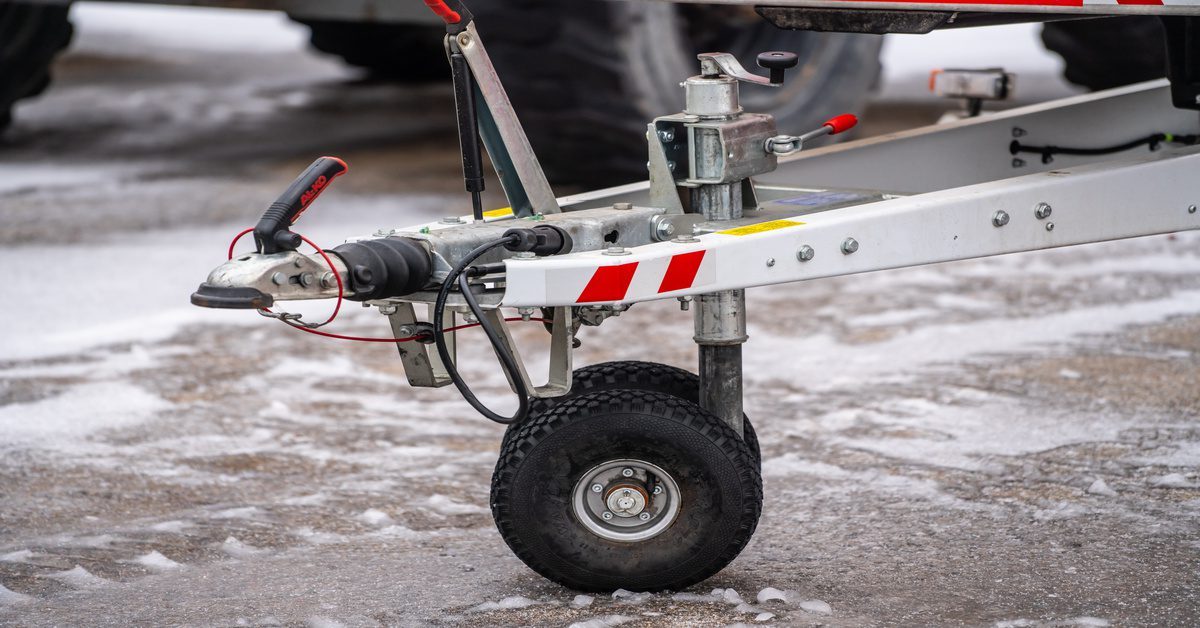 A gray trailer hitch with red stripes along its surface and various wires, cables, and levers for connecting a vehicle.